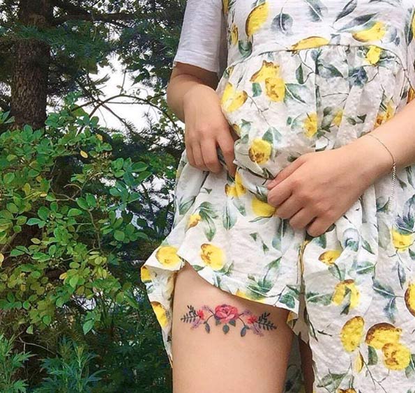 Elegant floral thigh tattoo by Zihee