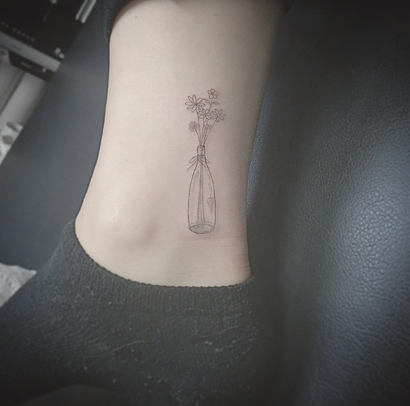 Flowers in a bottle tattoo by East Iz