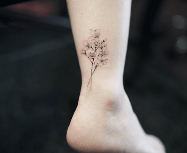 Colorless cherry blossom tattoo on ankle by Nando 