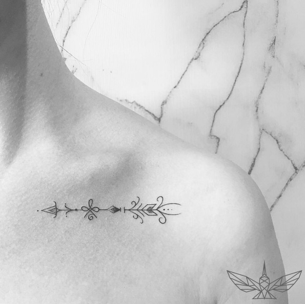 Playful arrow tattoo on collarbone by Cholo