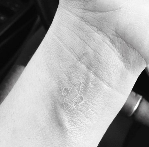White ink fleur-de-lis tattoo on wrist by Jon Boy