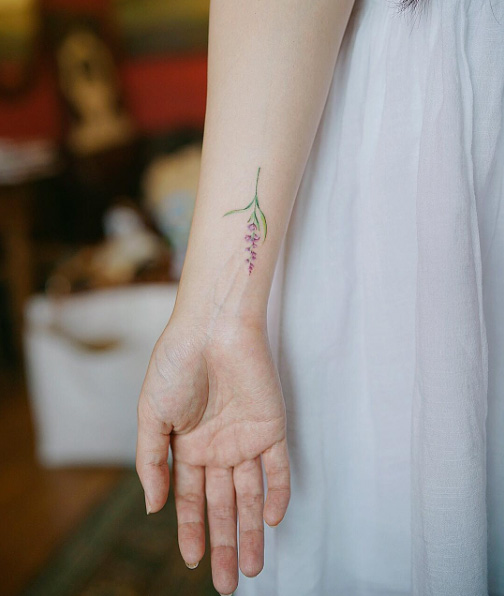 Elegant floral wrist tattoo by Nando