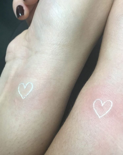 Matching white ink heart tattoos by Mary