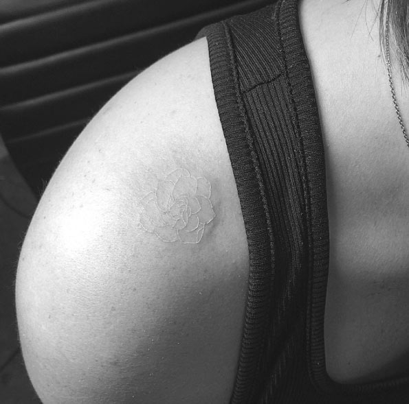 Minimalistic white ink rose tattoo on top shoulder by Jon Boy