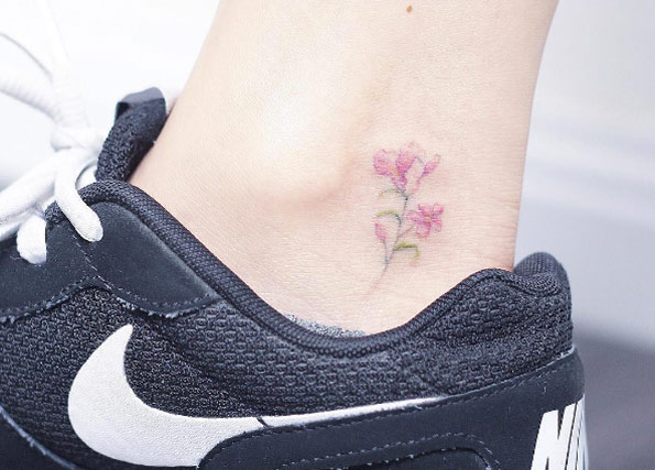 Tiny pink floral tattoo on ankle by Mini Lau
