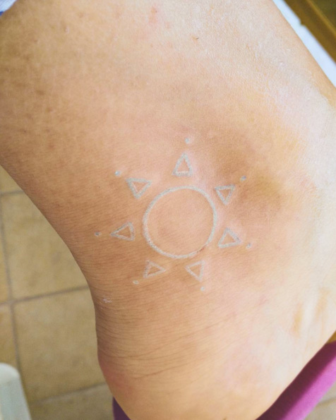 White ink sun tattoo on ankle via Lucy
