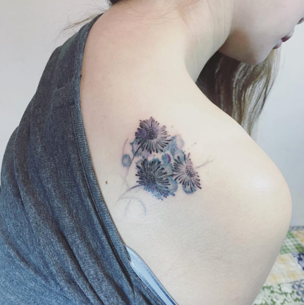 Watercolor daisies on back shoulder by Mojo Tattoo
