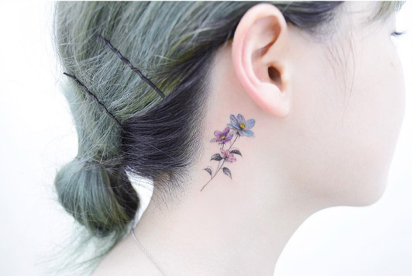 Colorful behind-the-ear flower tattoo by Tattooist Banul