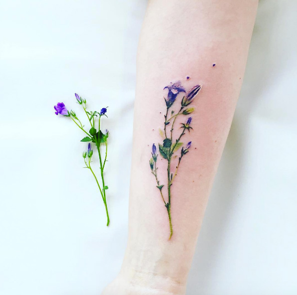 Hyper-realistic wildflower tattoo by Pis Saro