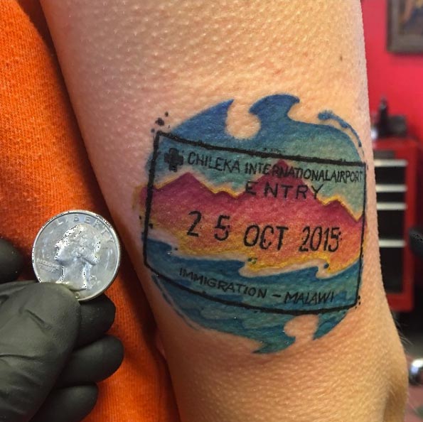 Watercolor passport stamp tattoo by Adam Poe