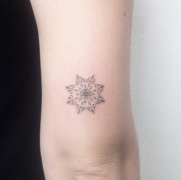 Tiny snowflake tattoo on tricep by Michaella Schorr