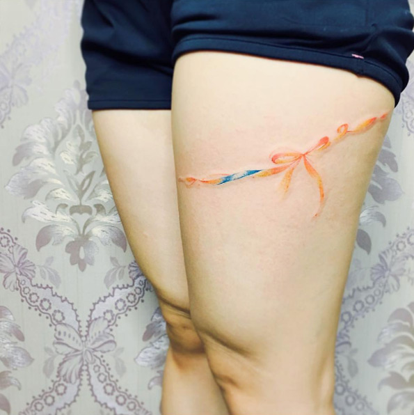Watercolor ribbon around thigh by There Tattoo