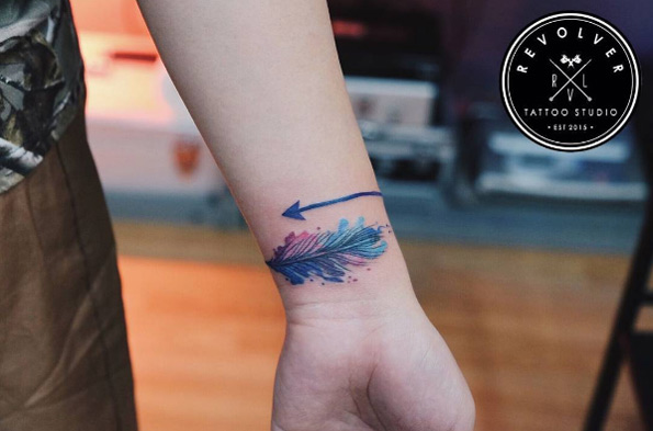 Watercolor arrow tattoo on wrist by Revolver