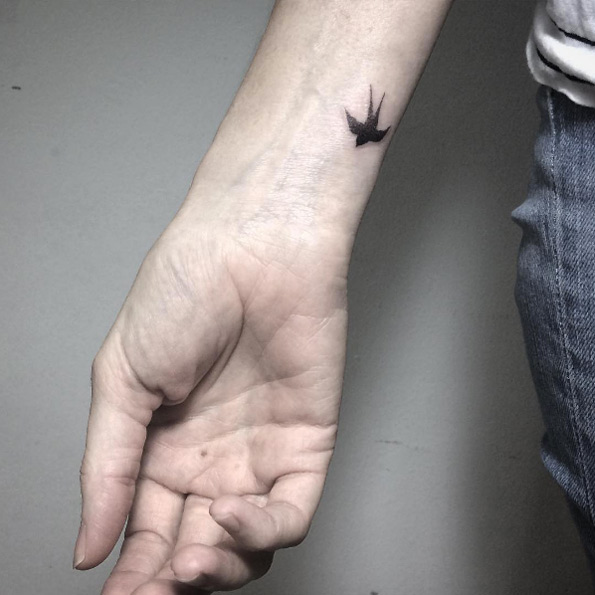 Tiny dotwork swallow on wrist by Fin Tattoos