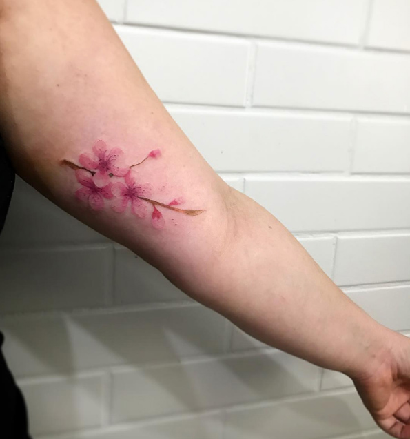 Cherry blossom tattoo on bicep by Junior Lopes