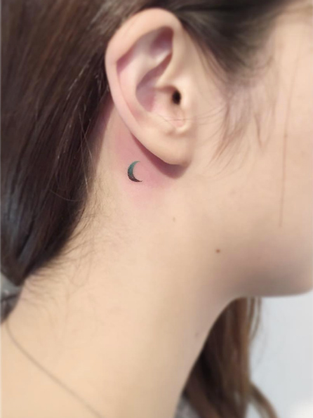 Small crescent moon tattoo behind ear by Playground Tattoo